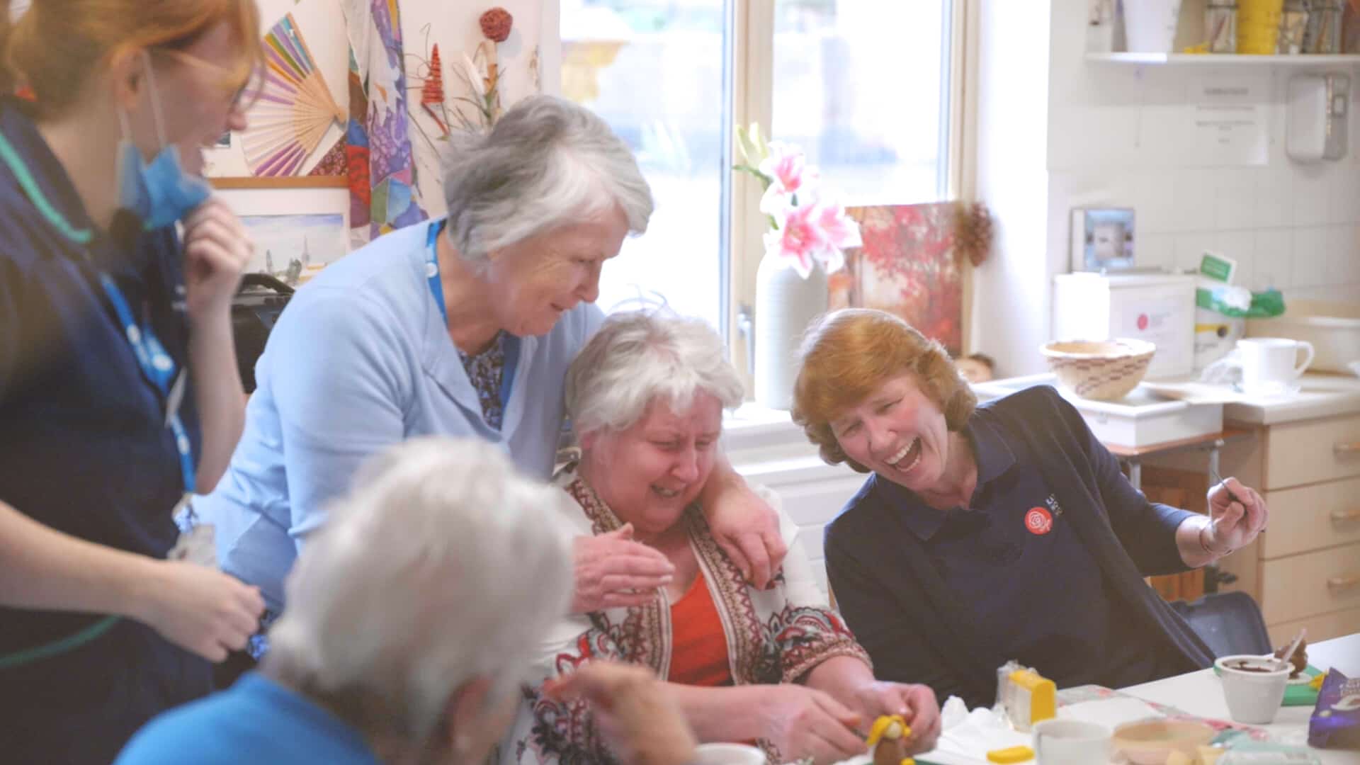 People laughing and enjoying a social gathering around a table.